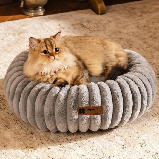 Cat lying on a gray plush pet bed with a brand label

